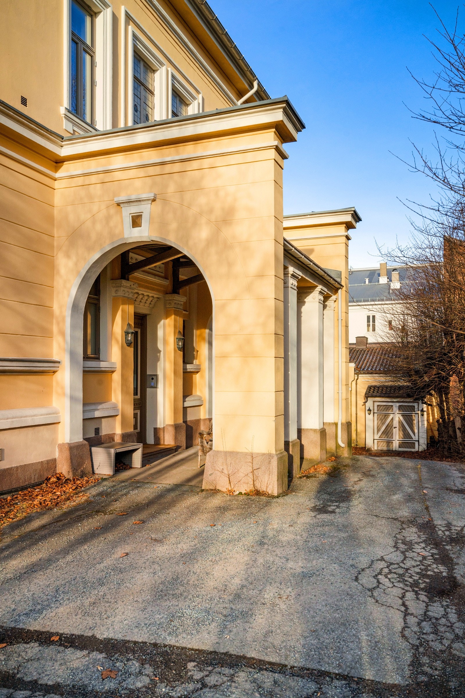 Inngangspartiet er overbygget og har en massiv, tofløyet ytterdør i eik med doble glassfelt. Glassene er farget og har vakkert, intrikat mønster. Galleribilde