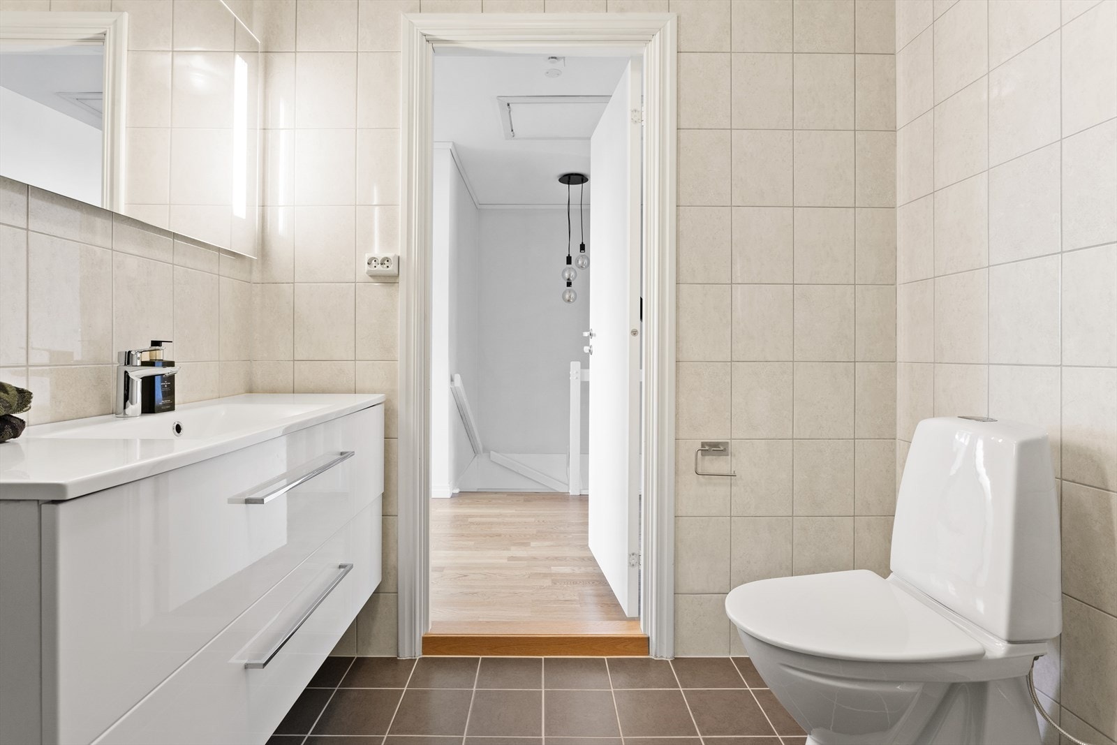 Speil med belysning i overkant av servant, oppbevaringsskap på vegg og varmekabler i gulv. Galleribilde