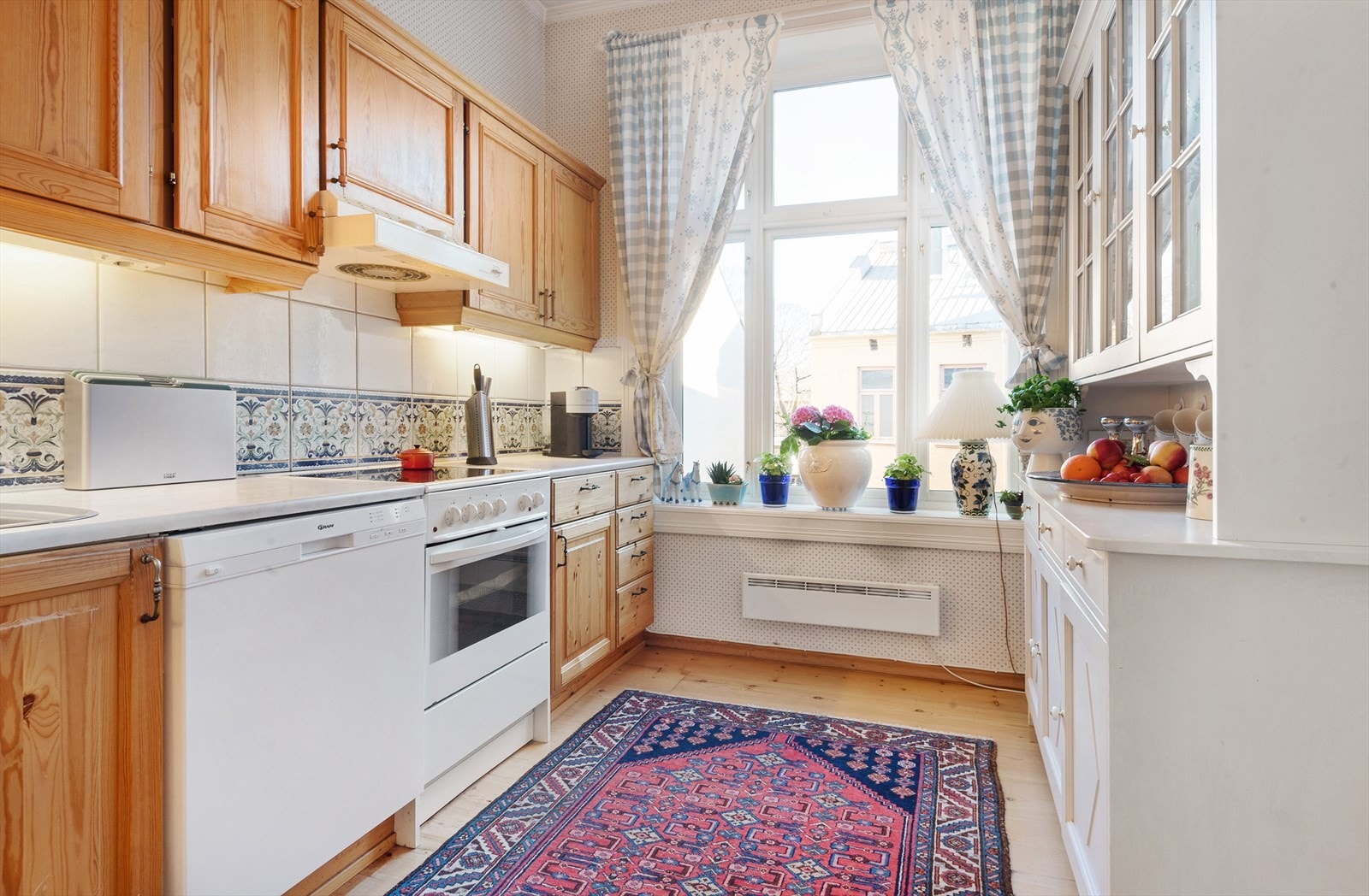 HTH kjøkken med profilerte furufronter, benkeplate med nedfelt vaskekum og fliser over benk. Galleribilde