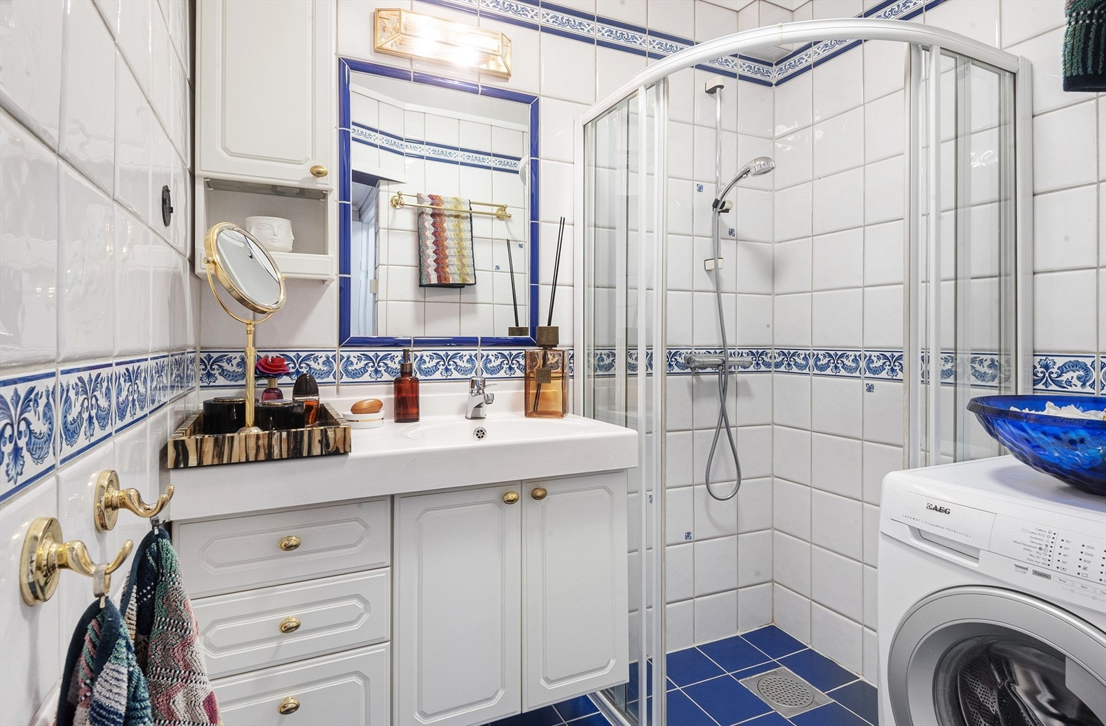 Bad fra 1990 tallet med dusjhjørne med dører i herdet glass, benkeplate med servant og veggskap. Galleribilde