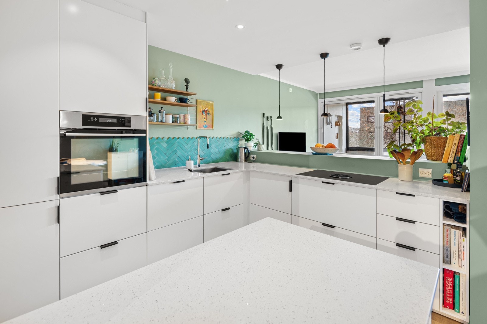 Lekkert kjøkken med glatte fronter og benkeplate i komposittstein med nedfelt kum i stål. Galleribilde