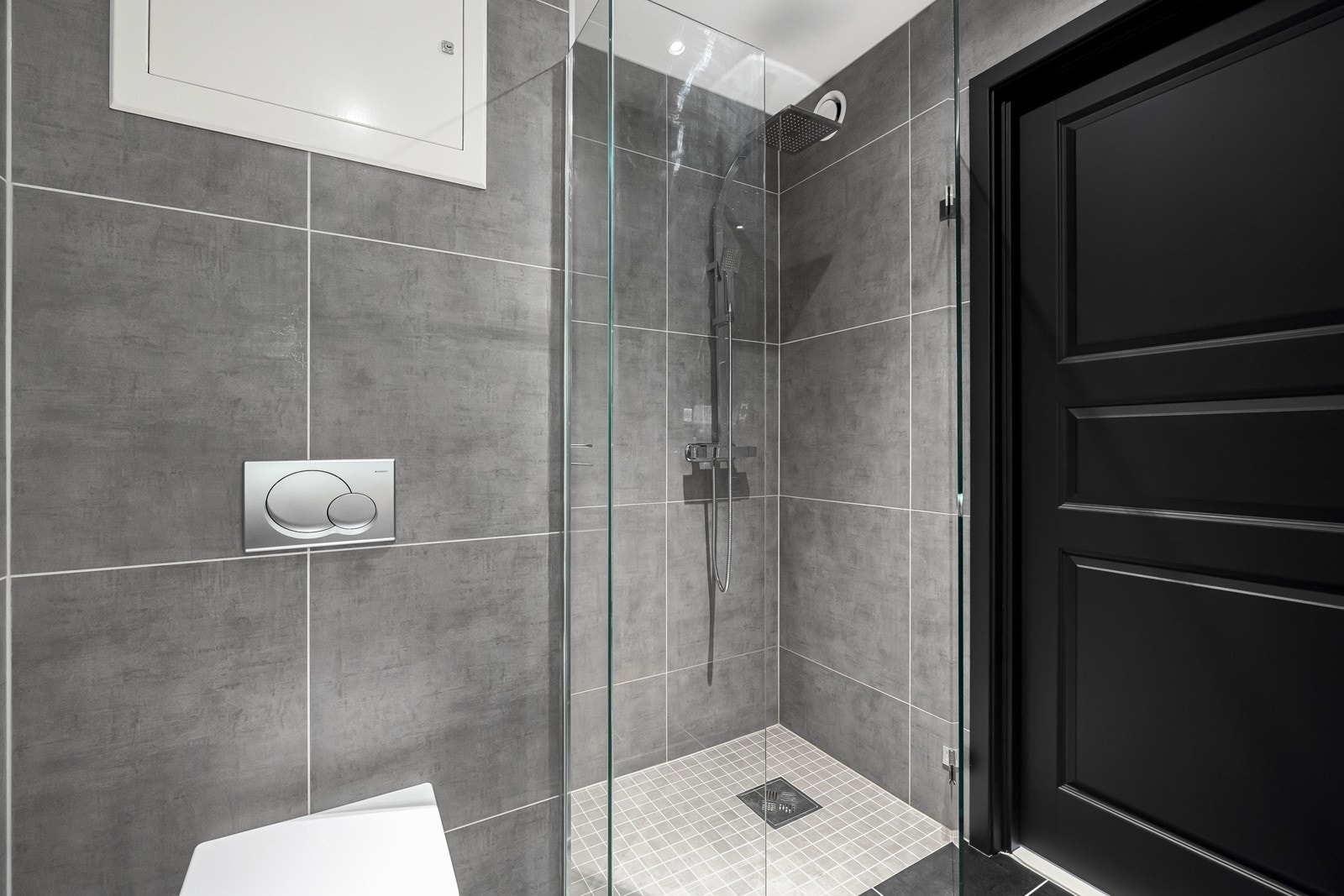 Videre inneholder badet dusjnisje med glassdører og veggmontert klosett. Galleribilde