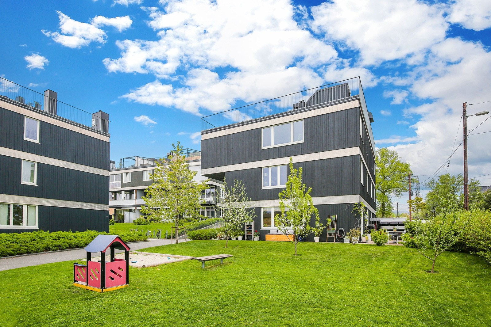 Sommerbilde av borettslaget - Hele området er inngjerdet og bilfritt med flere lekearenaer for de minste. Galleribilde