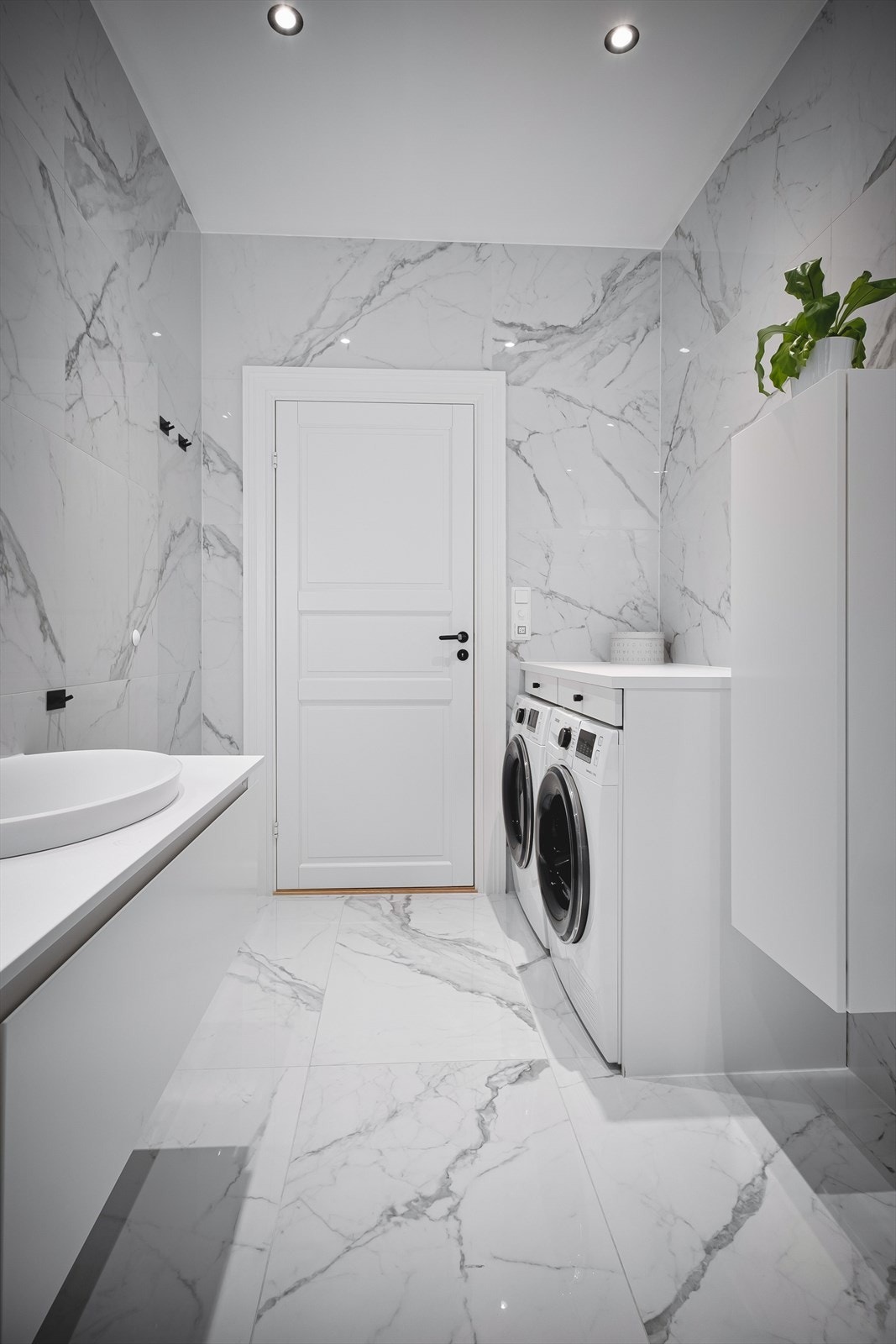 Innredning og garnityr på bad med veggmontert toalett, dusjhjørne med glassvegger og regnfallsdusj og to servanter av Corian med ettgreps blandebatteri. Galleribilde