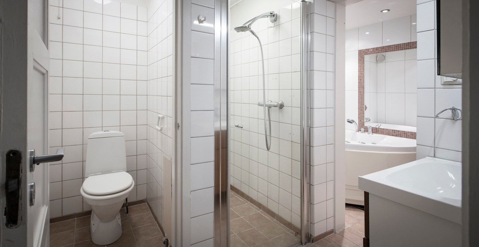 Baderom med flislagt gulv med varme og flislagte vegger. Himling med panel og malt flate med downlights. Galleribilde