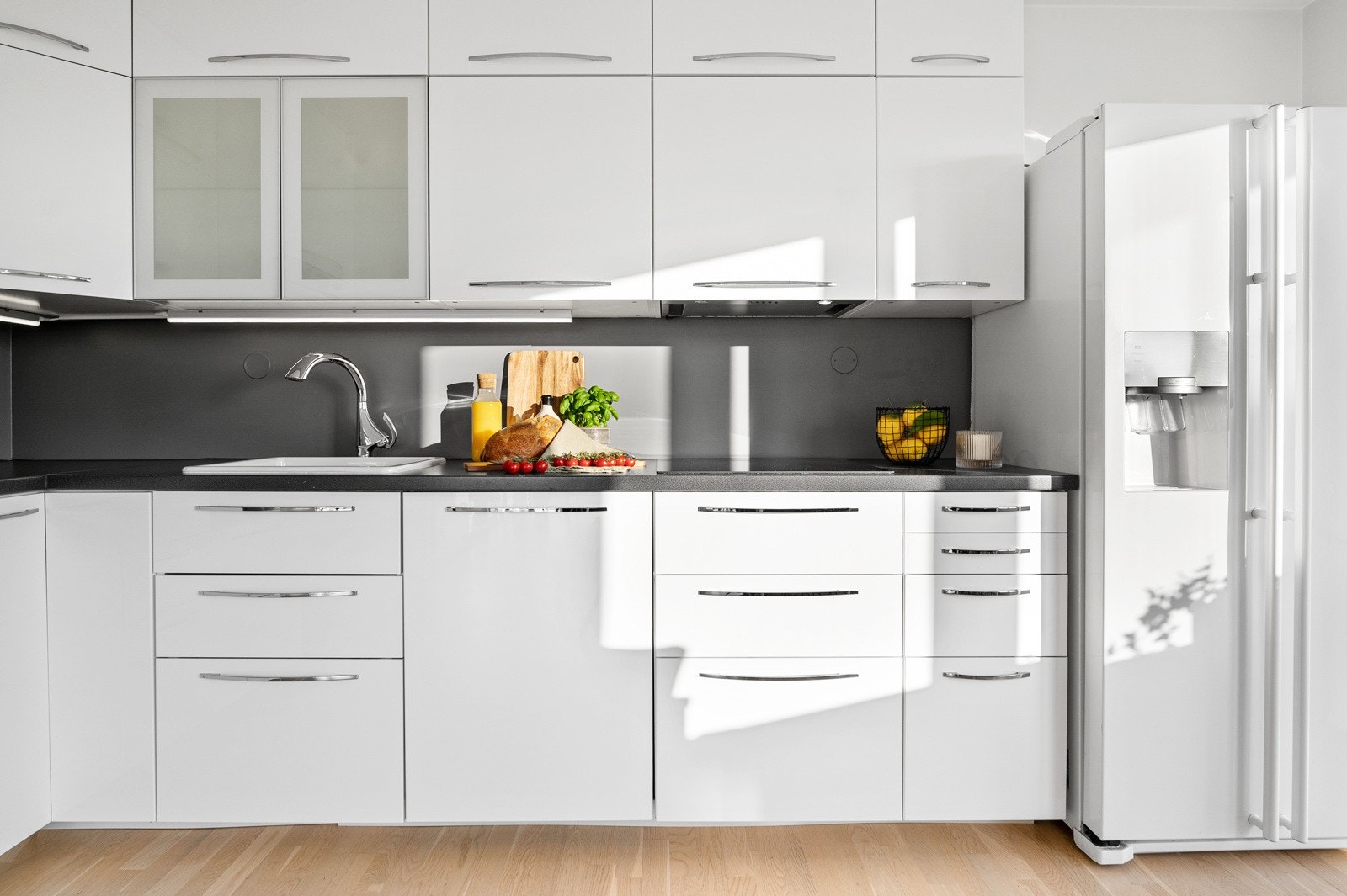 Innredningen har glatte fronter i høyglans og benkeplate i laminat. Side-by-side kjøleskap med isbitfunksjon vil følge boligen ved salg. Galleribilde