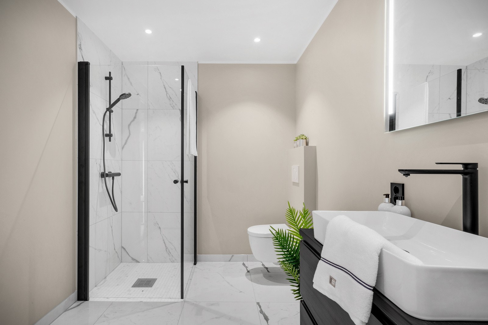 Badet er innredet med vegghengt wc, dusj med glass foldedør, servant med møblement, speil og belysning. Galleribilde