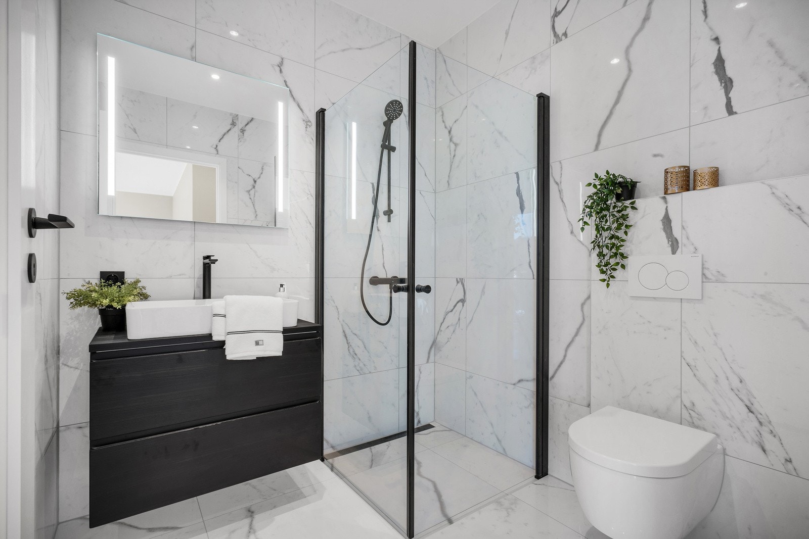 Rommet er innredet med vegghengt wc, dusj med glass foldedører, servant med møblement, speil og belysning. Spotlights i tak. Galleribilde