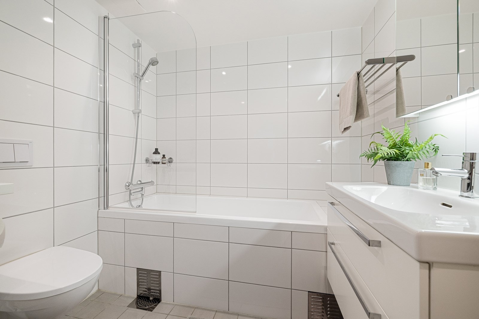 Pent innfliset badekar, med veggfestet dusjgarnityr. Galleribilde