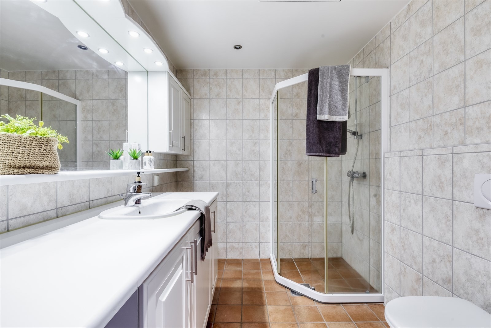 Bad med varmekabler i gulv, dusjnisje, speil, benk og skap Galleribilde