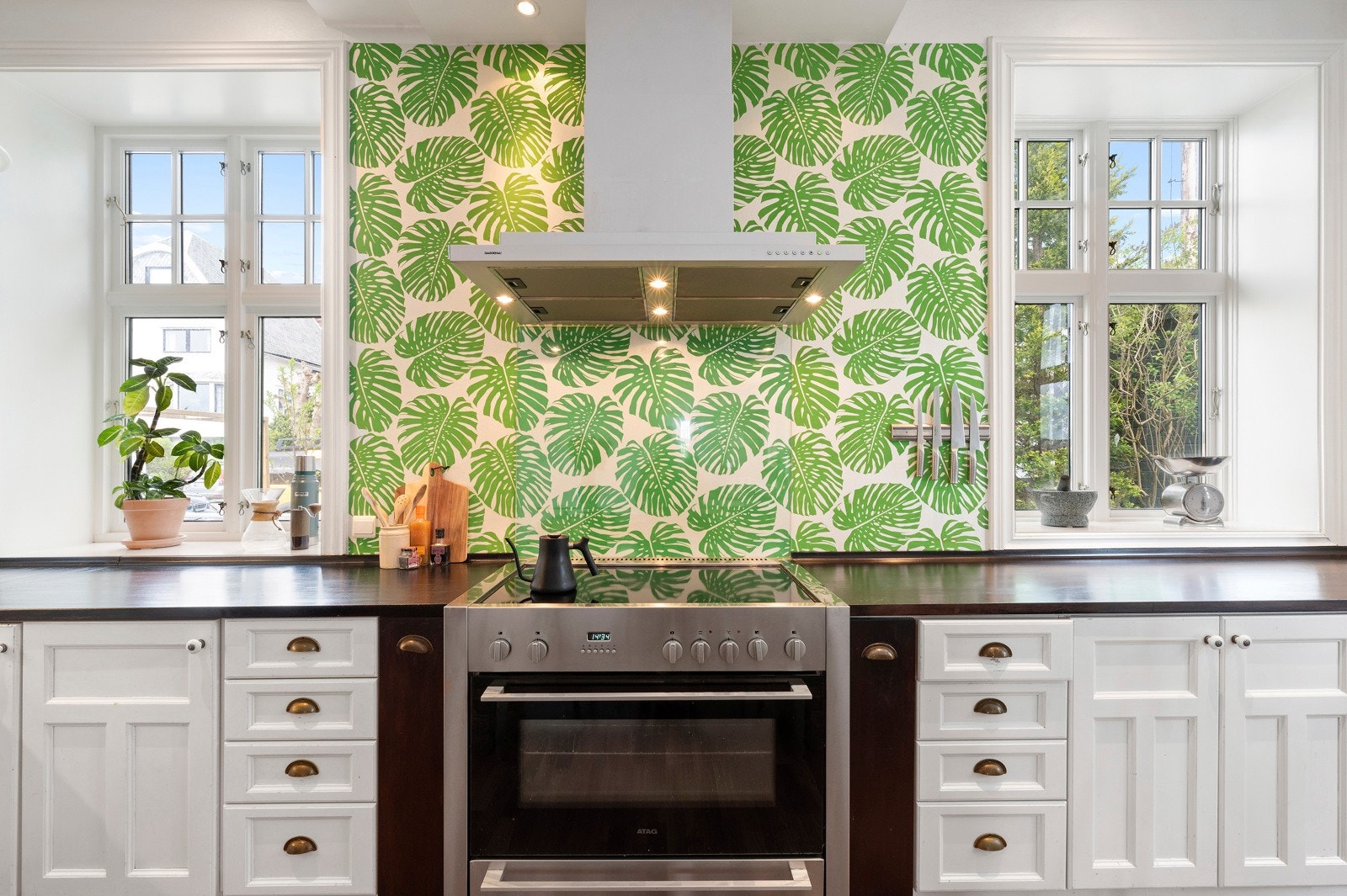 Kokesonen har en fargesprek tapet med bladmotiv, en stor ventilatorhette fra Gaggenau og en bred komfyr fra ATAG. Galleribilde