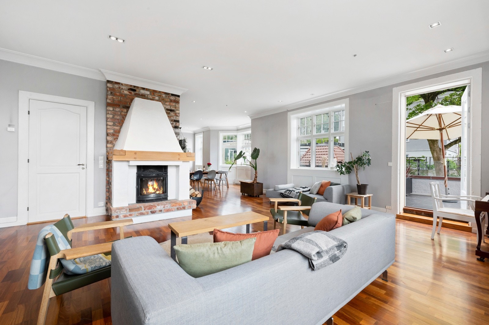 Stuen har en murt, sjarmerende peis med hvitmalt puss, teglstein, trebjelke og peisinnsats med stort flammebilde. Galleribilde