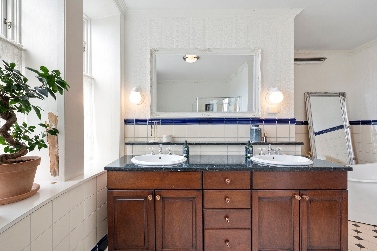 Rommet har et stort elegant baderomsmøblement i brunt tre med granittbenkeplate og to nedfelte servanter med togreps vannkran. Galleribilde