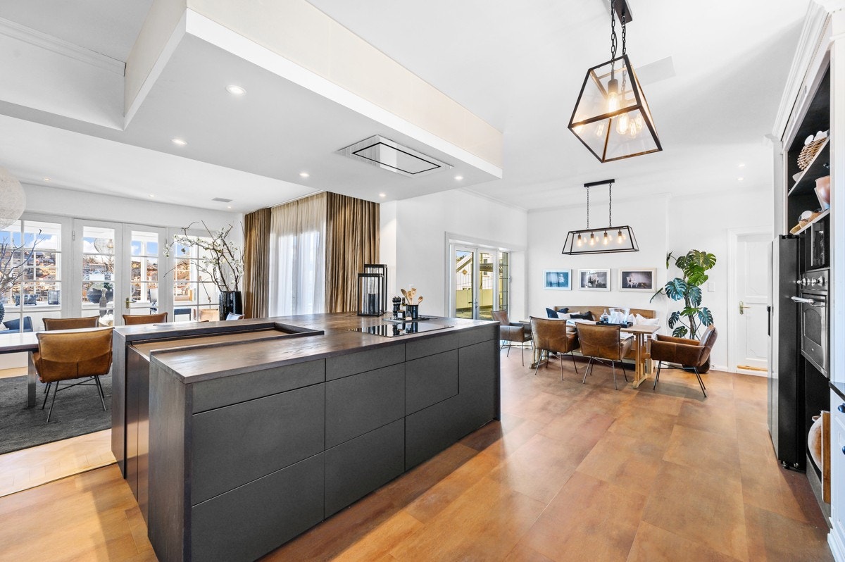 Lyst, åpent og luftig kjøkken med egen spiseplass, kjøkkenøy og åpen løsning mot spisestuen Galleribilde