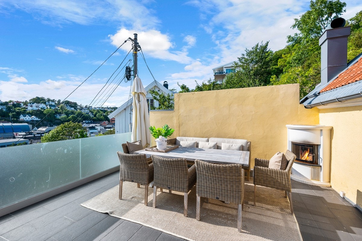 Solrik og skjermet uteplass med peis ved bassenget Galleribilde