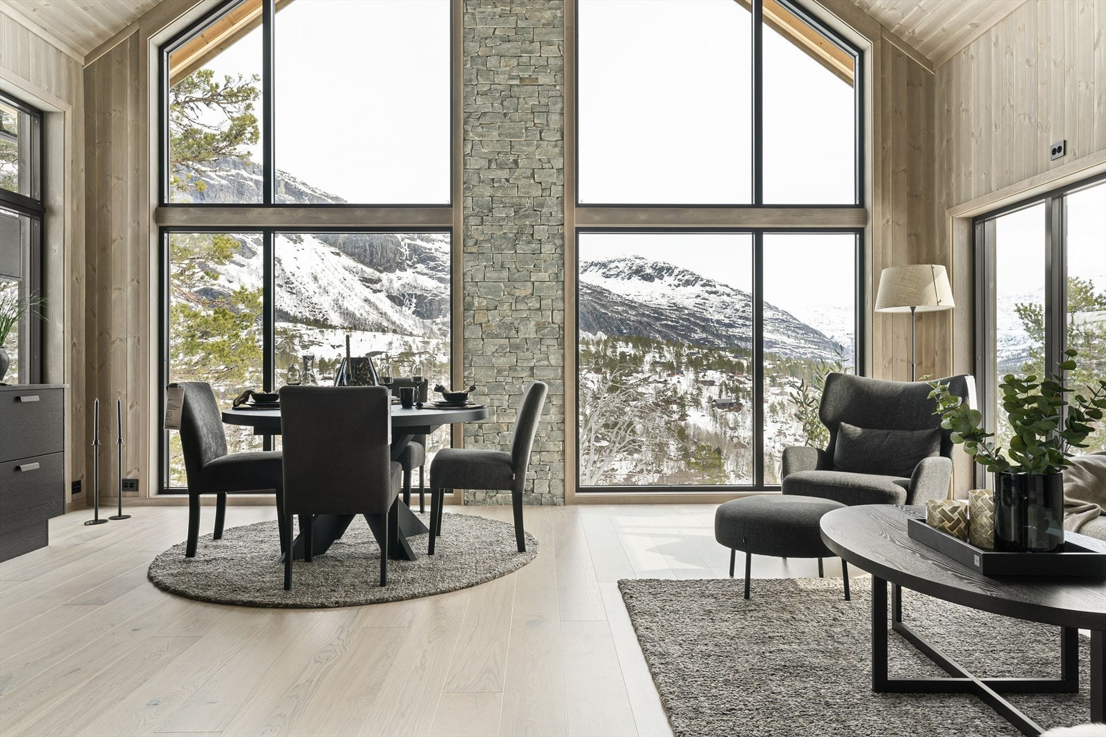 Inne åpner en moderne hytte seg med store vinduer som slipper naturen, lyset og luften inn til romslige oppholdsrom Galleribilde