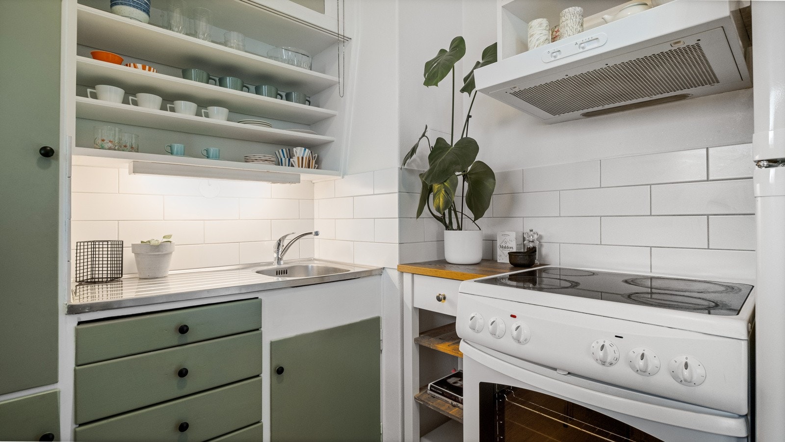 Kjøkkenet har komfyr, ventilator over stekesone, blandebatteri og vask i rustfritt stål. Galleribilde