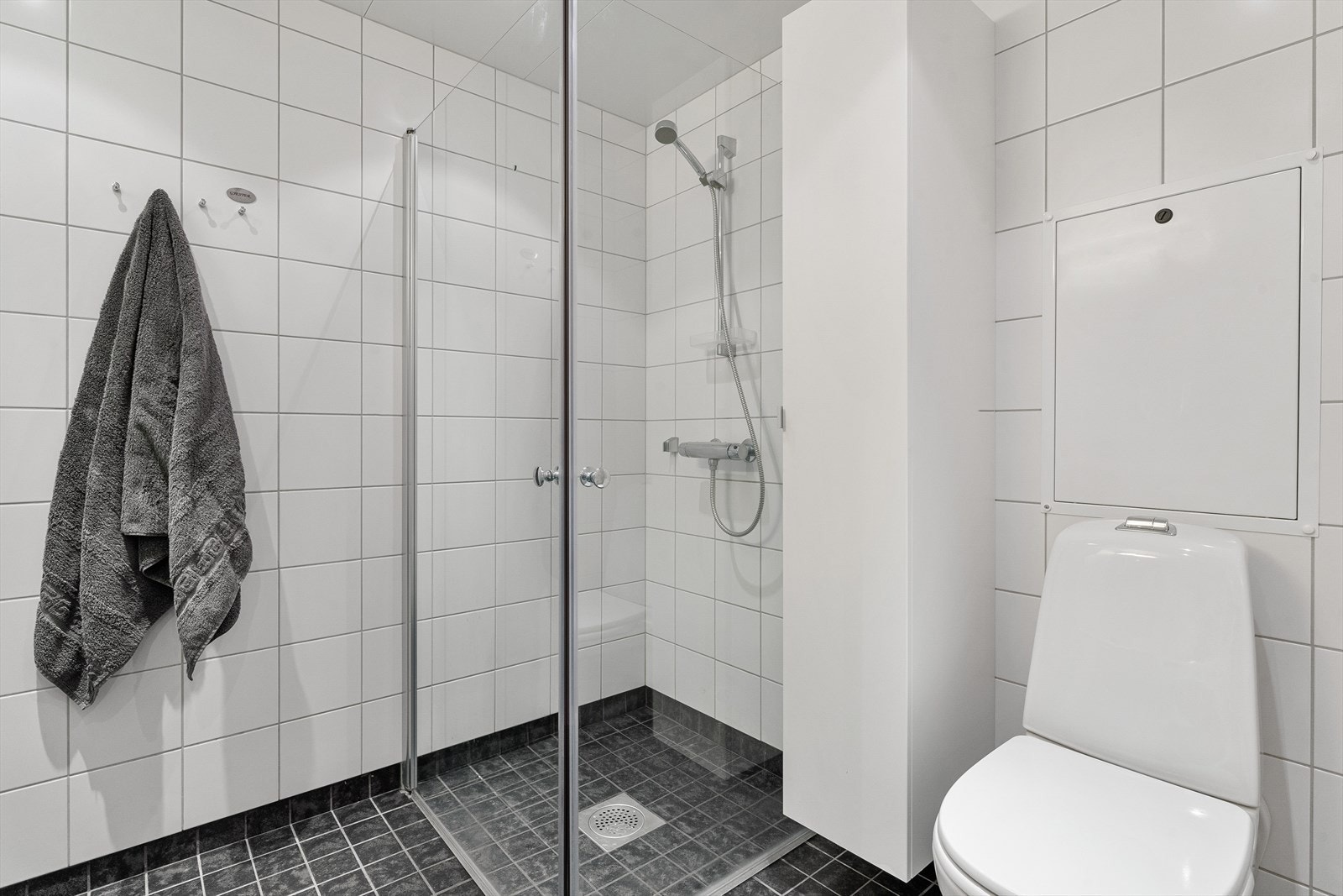 Badet er innredet med dusjhjørne, servantinnredning med skap og vegghengt toalett. Galleribilde