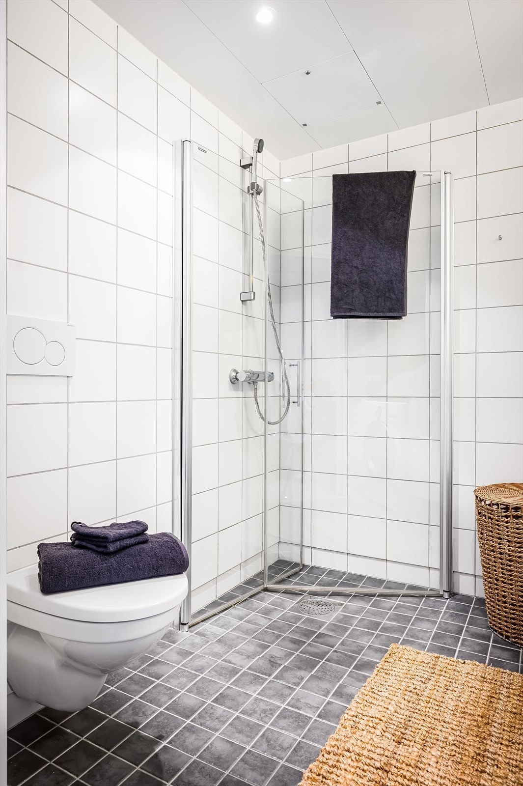 Badet er utstyrt med vegghengt toalett og dusjhjørne med innfellbare glassdører i herdet glass Galleribilde