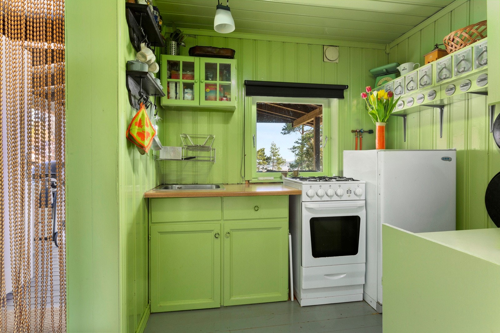 På kjøkkenet er det malt kjøkkeninnredning, benkeplate i laminat, gasskomfyr og kjøleskap samt vask med avrenning til terreng. Galleribilde