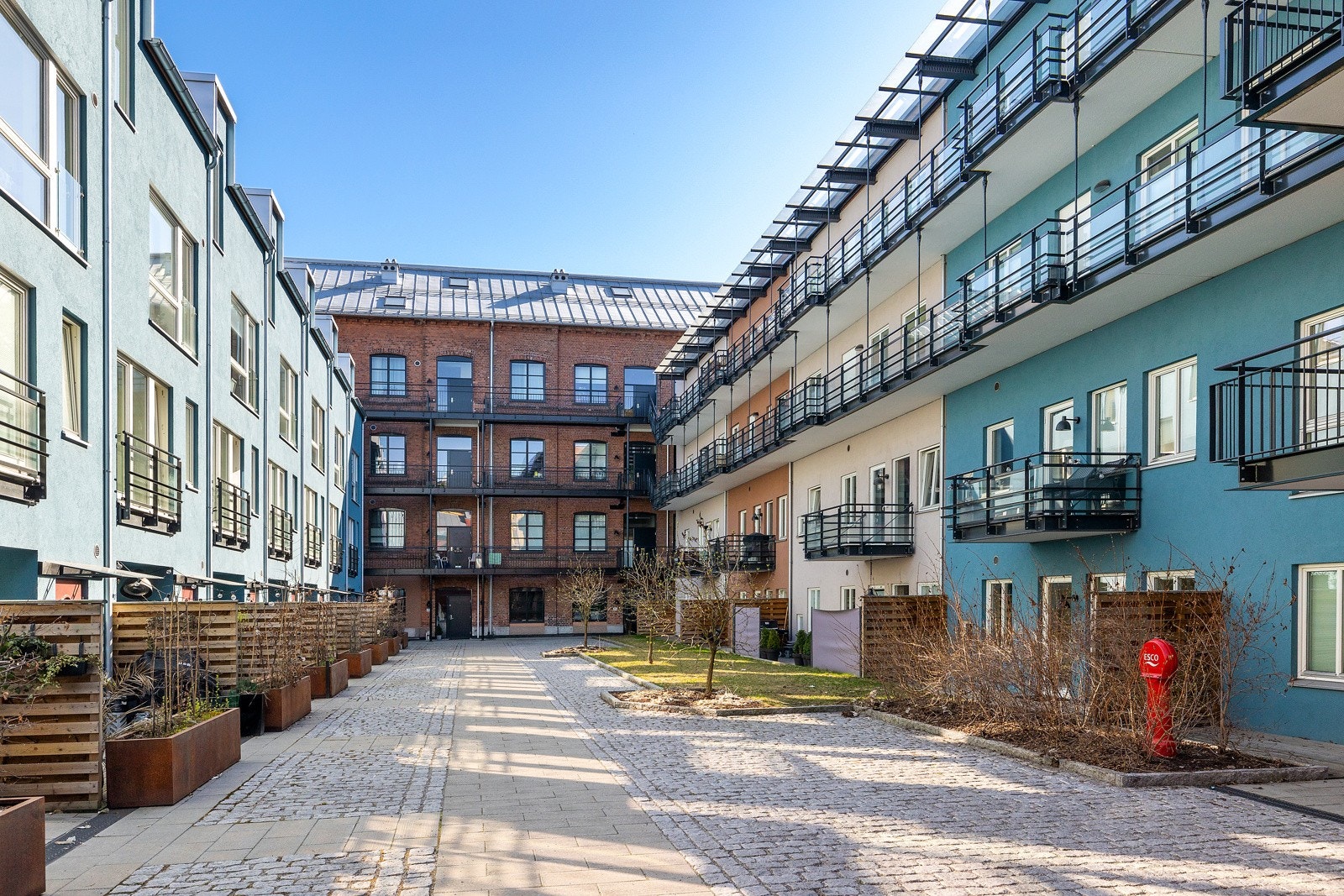 Skjermet bakgård som er pent opparbeidet med brostein, gressplen og beplantning. Galleribilde