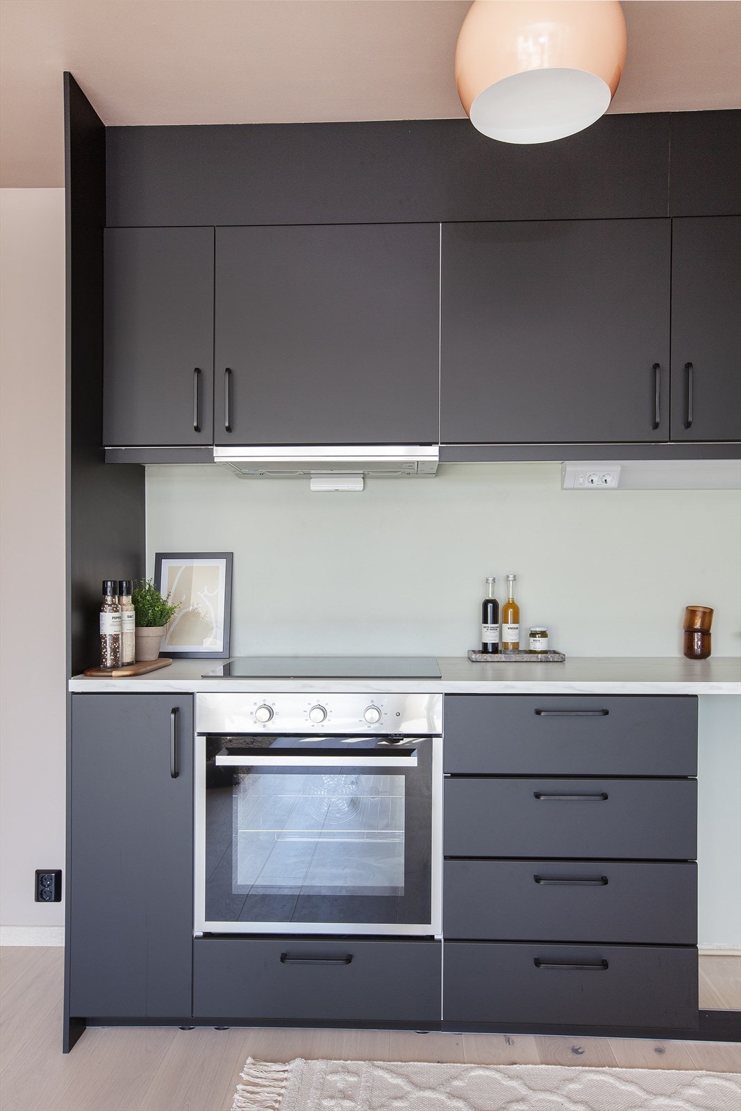 Nytt lekkert kjøkken med innredning fra IKEA med sorte matte fronter. Belysning og stikkontakt over kjøkkenbenk. Galleribilde