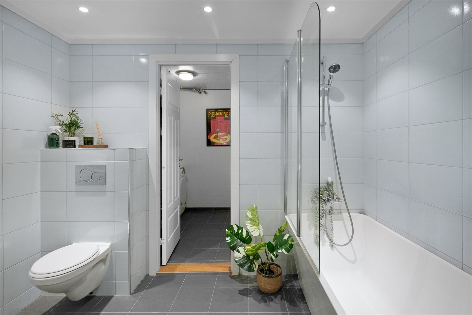 Det største badet har fliser i gråtone på gulv, lyse fliser på vegger og malt innvendig tak med led-downlights. Galleribilde