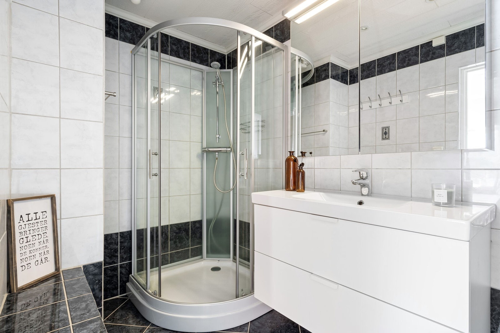 Badet er innredet med en tidløs innredning, servant, dusjkabinett og WC. Galleribilde