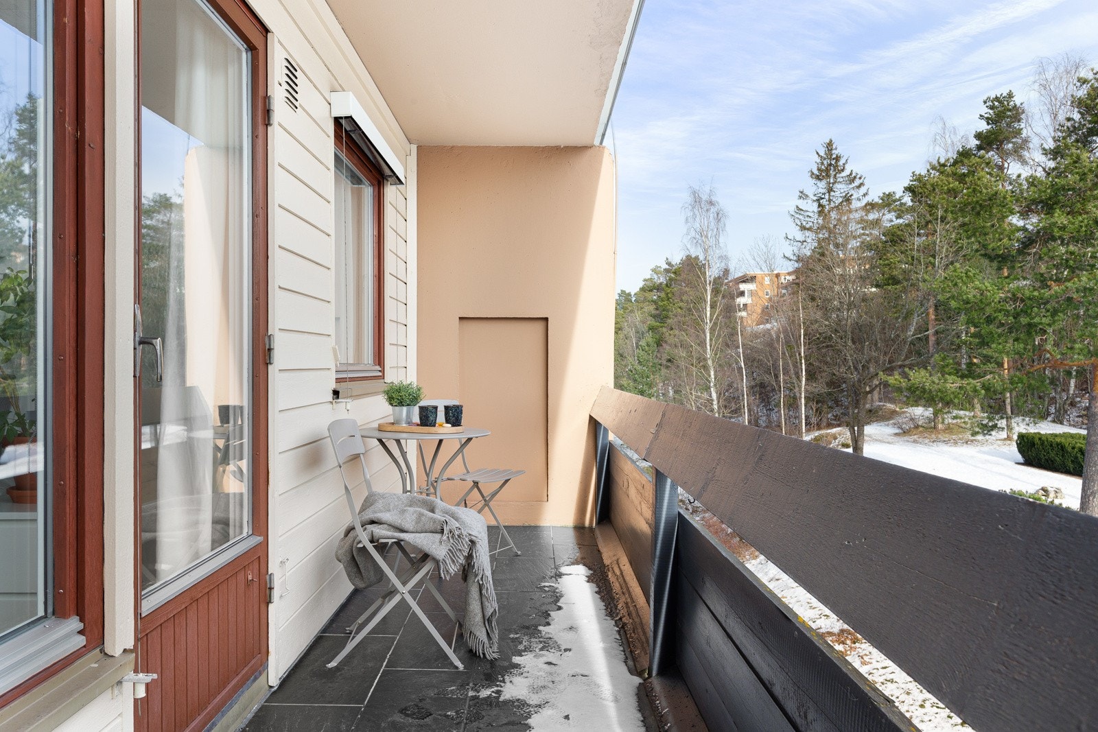 Leilighetens østvendte terrasse har flislagt dekke og rekkverk i tre. Galleribilde