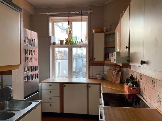 Kjøkken med mye skapplass med utsikt til grønn og stille bakgård. Galleribilde
