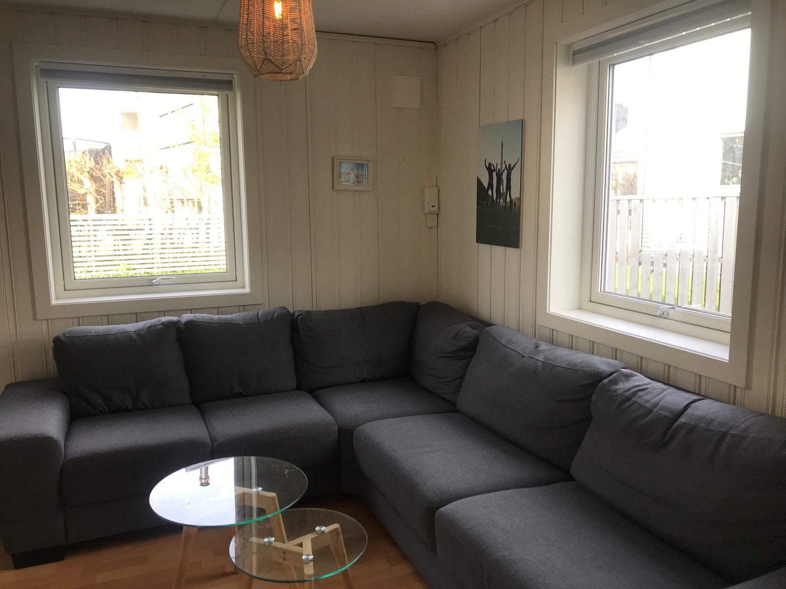 Lys stue med vegghengt TV, sofa og vindu på to sider Galleribilde