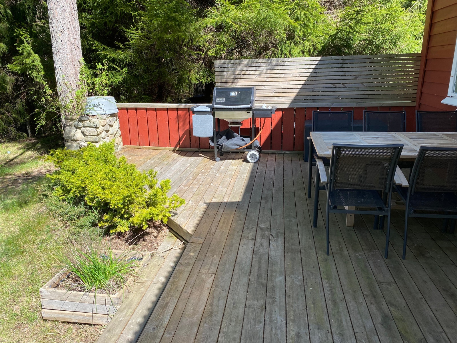 Stor platting med spiseplass og gassgrill samt komfortable sittestoler med puter Galleribilde