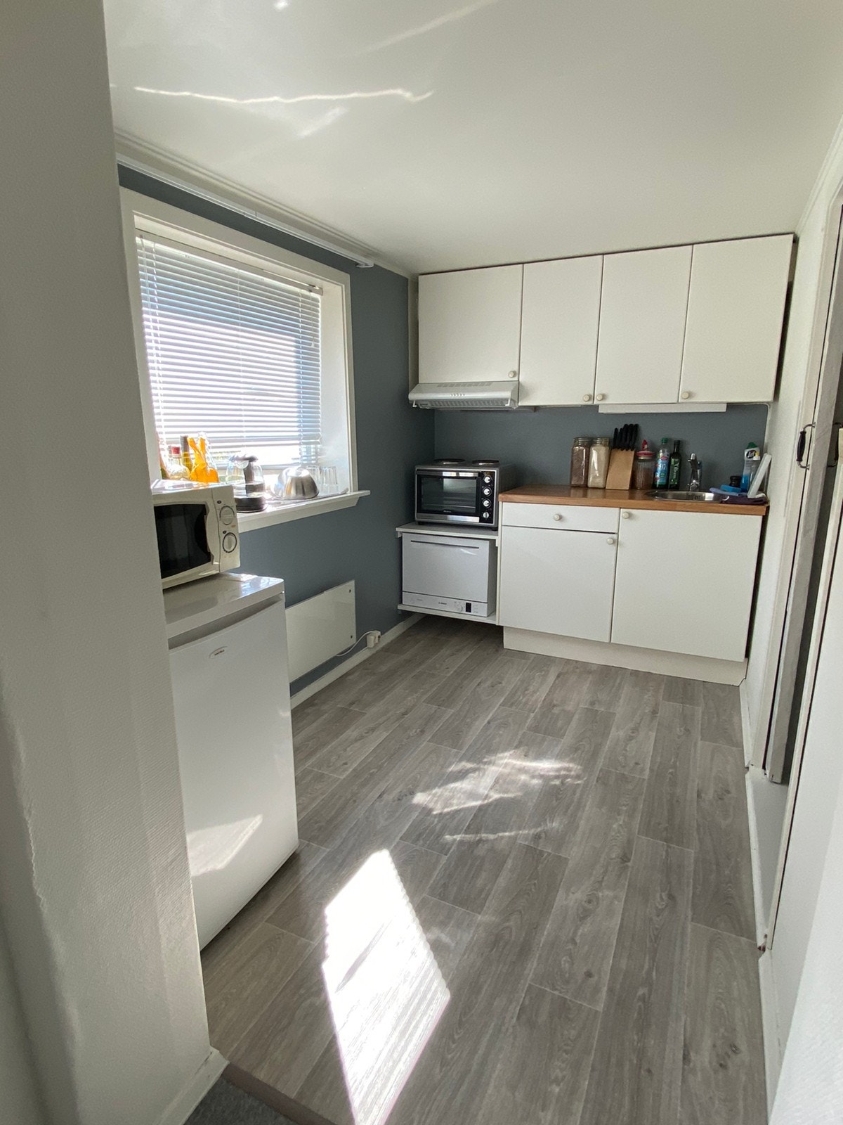 Kjøkken med liten oppvaskmaskin, mikrobølgeovn og kjøleskap, bilde fra tidligere. Oppgraderes nå med ny platetopp og stekeovn. Galleribilde