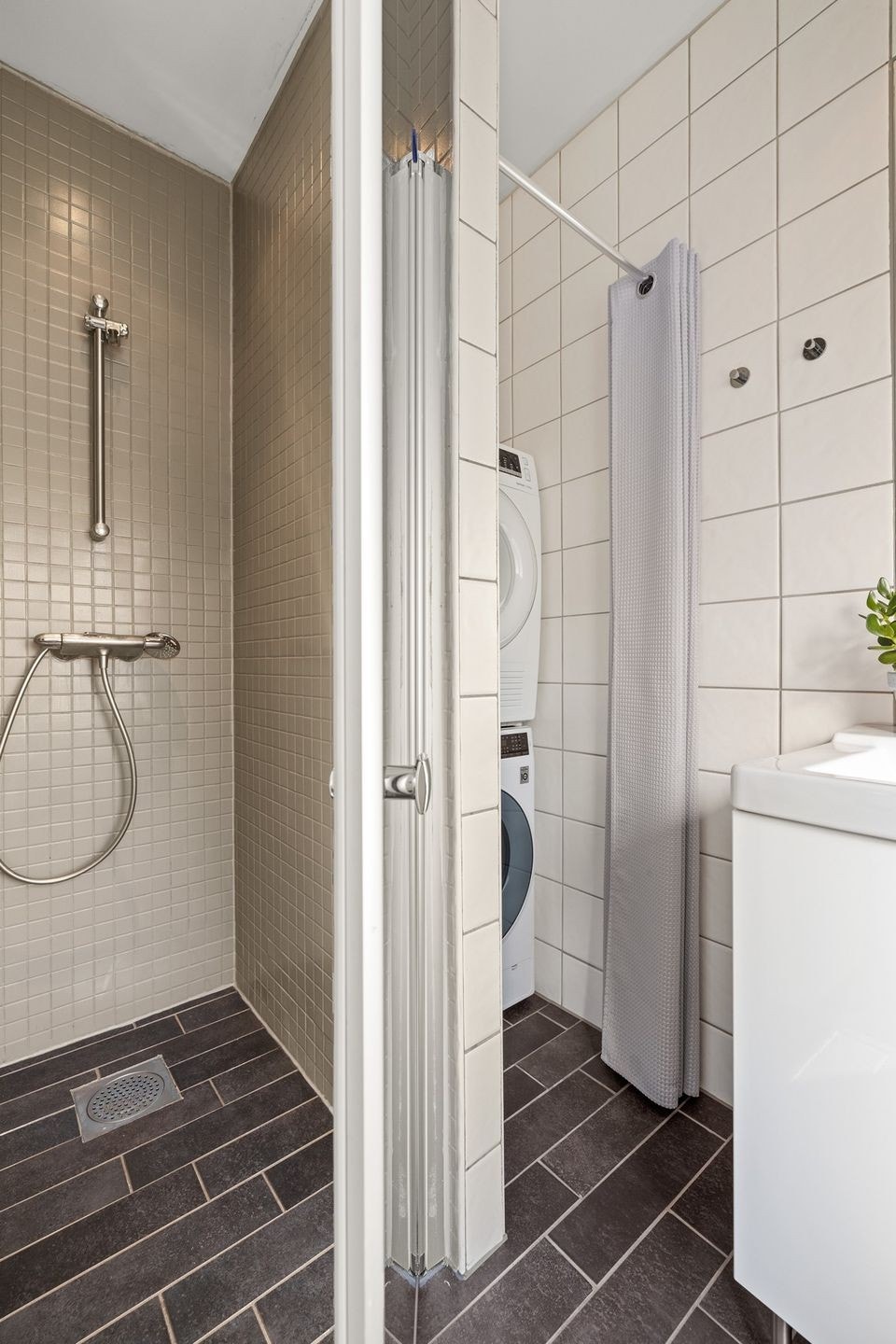 Badet har dusjnisje med glassvegg samt vaskemaskin og tørketrommel Galleribilde