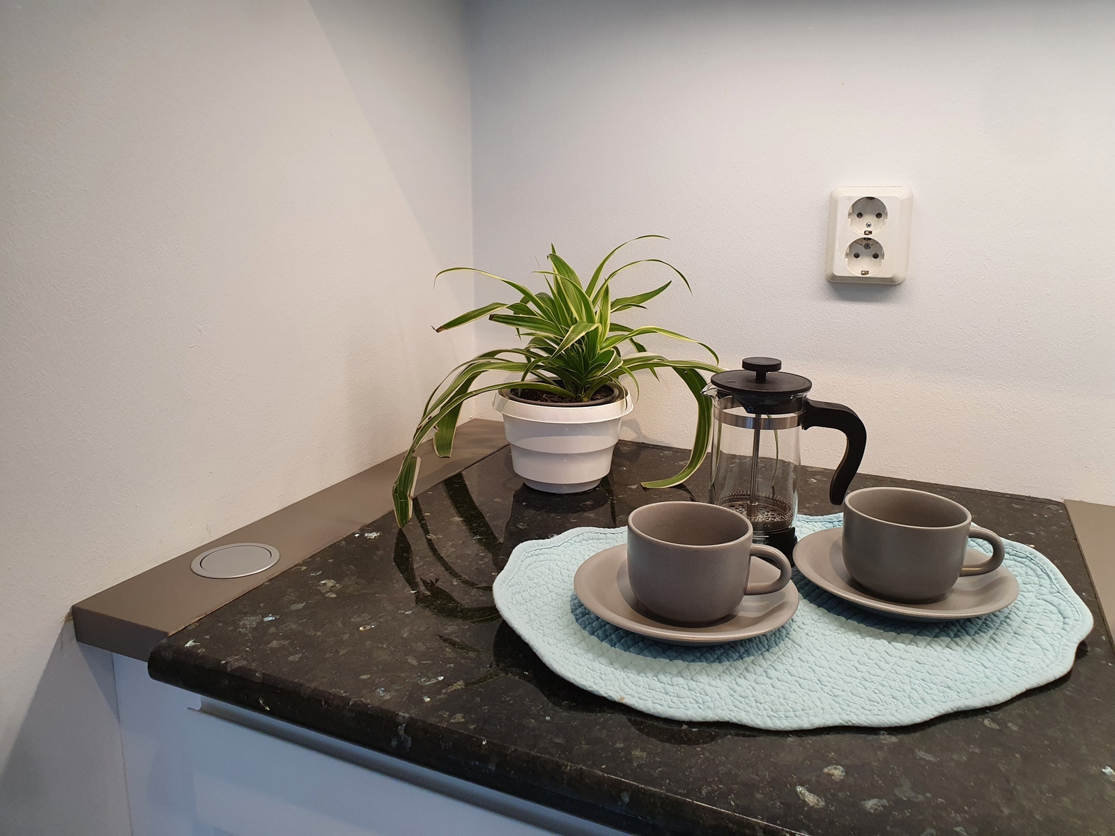 Kjøkkenbenken har fått en 60 cm stenplate av granittsorten "Larvikiitt" for å forlenge levetiden til resten av benkeplaten som er av typen Fenix Grigio Londra. Galleribilde