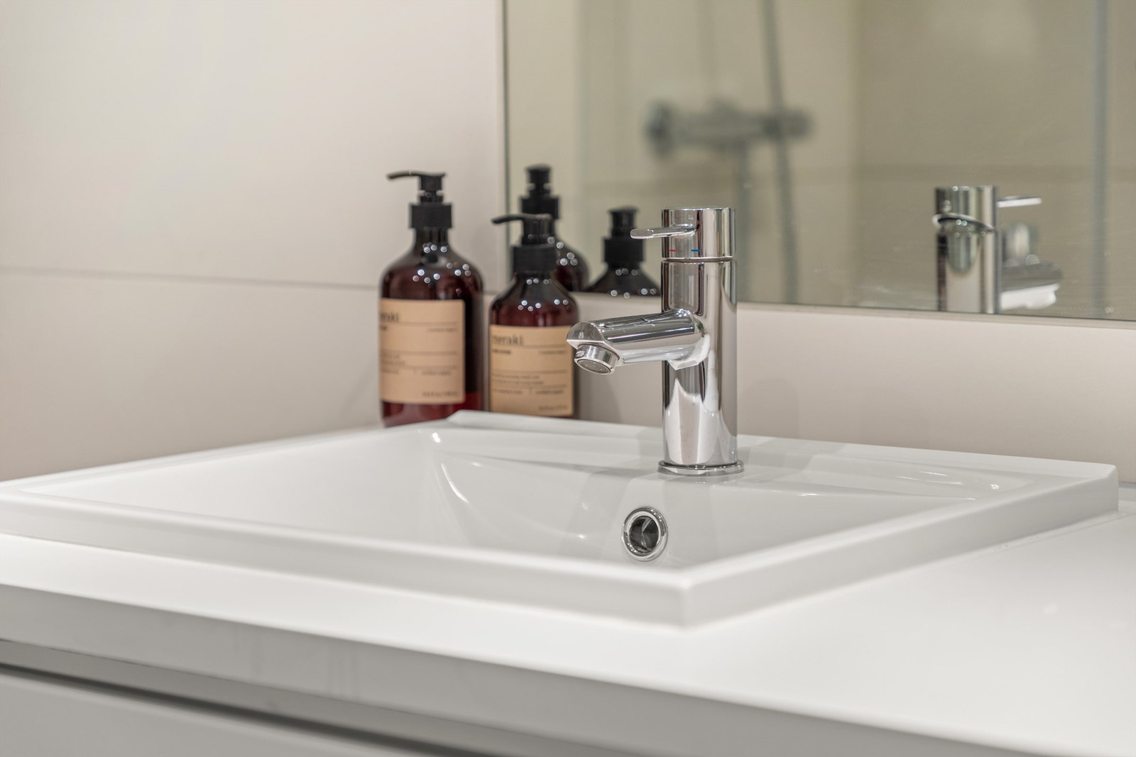 Laminat benkeplate med skuffeinnredning samt vaskemaskin under. Ovenpåliggende servant med ett-greps armatur. Galleribilde