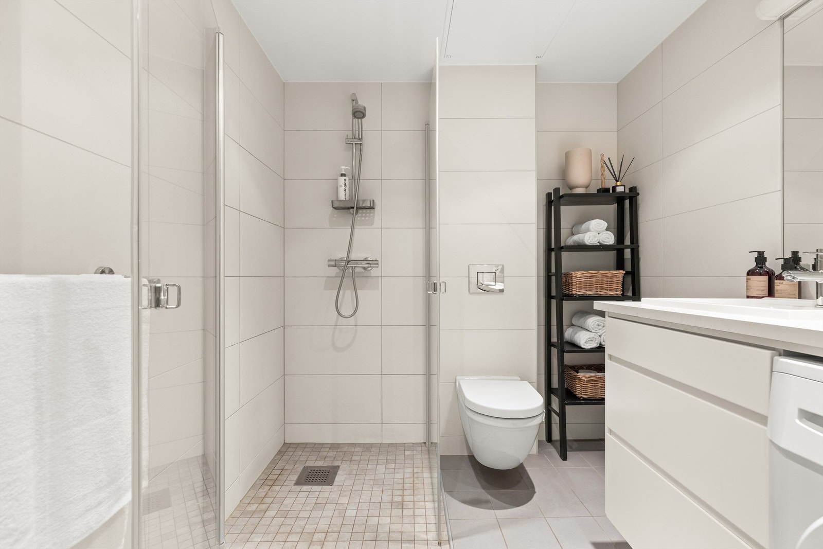 Dusjhjørne med innfellbare glassdører og to-greps armatur. Vegghengt toalett. Galleribilde