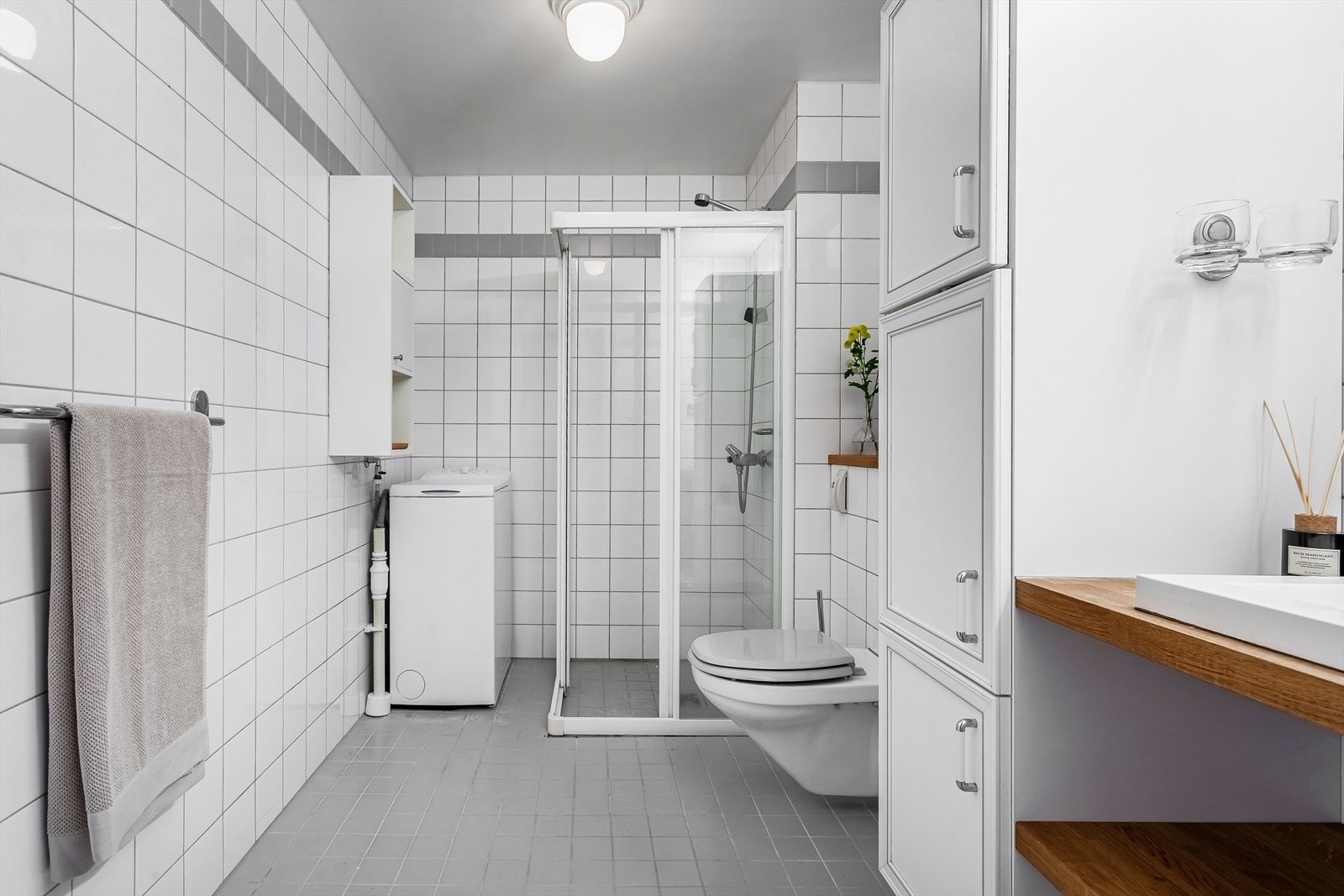 Pent flislagt bad med gulvvarme, vegghengt klosett, dusjhjørne og opplegg vaskemaskin Galleribilde