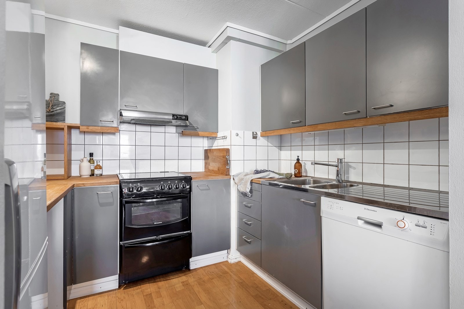 Kjøkkeninnredning med heltre benkeplate og fliser over benk. Opplegg oppvaskmaskin Galleribilde