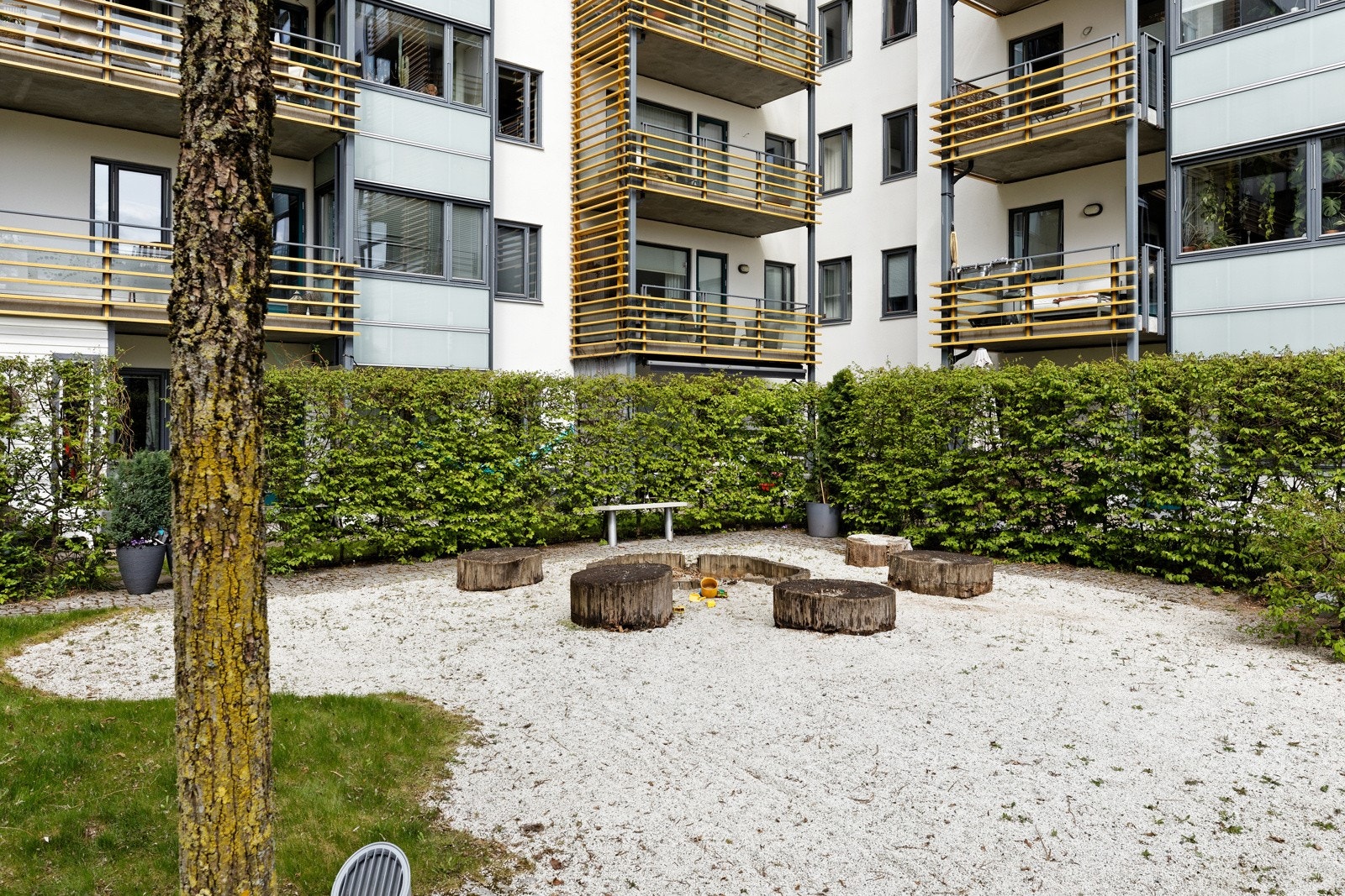 Pent opparbeidet felles tomtegrunn med stensatte gangarealer og grøntanlegg med diverse busker og beplantninger, sittegrupper og gangveier Galleribilde