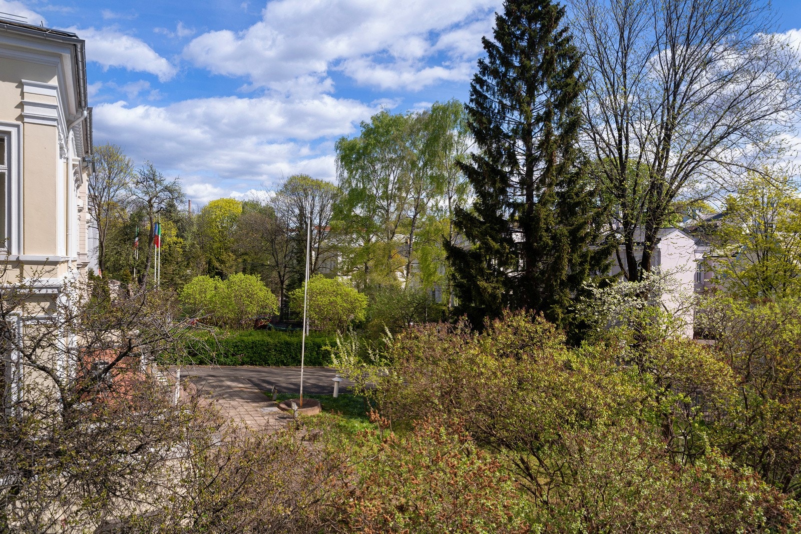 Tomtegrunnen er avgrenset med gjerde og flott opparbeidet med plen, beplantning, brostein, trær og skulptur. Galleribilde
