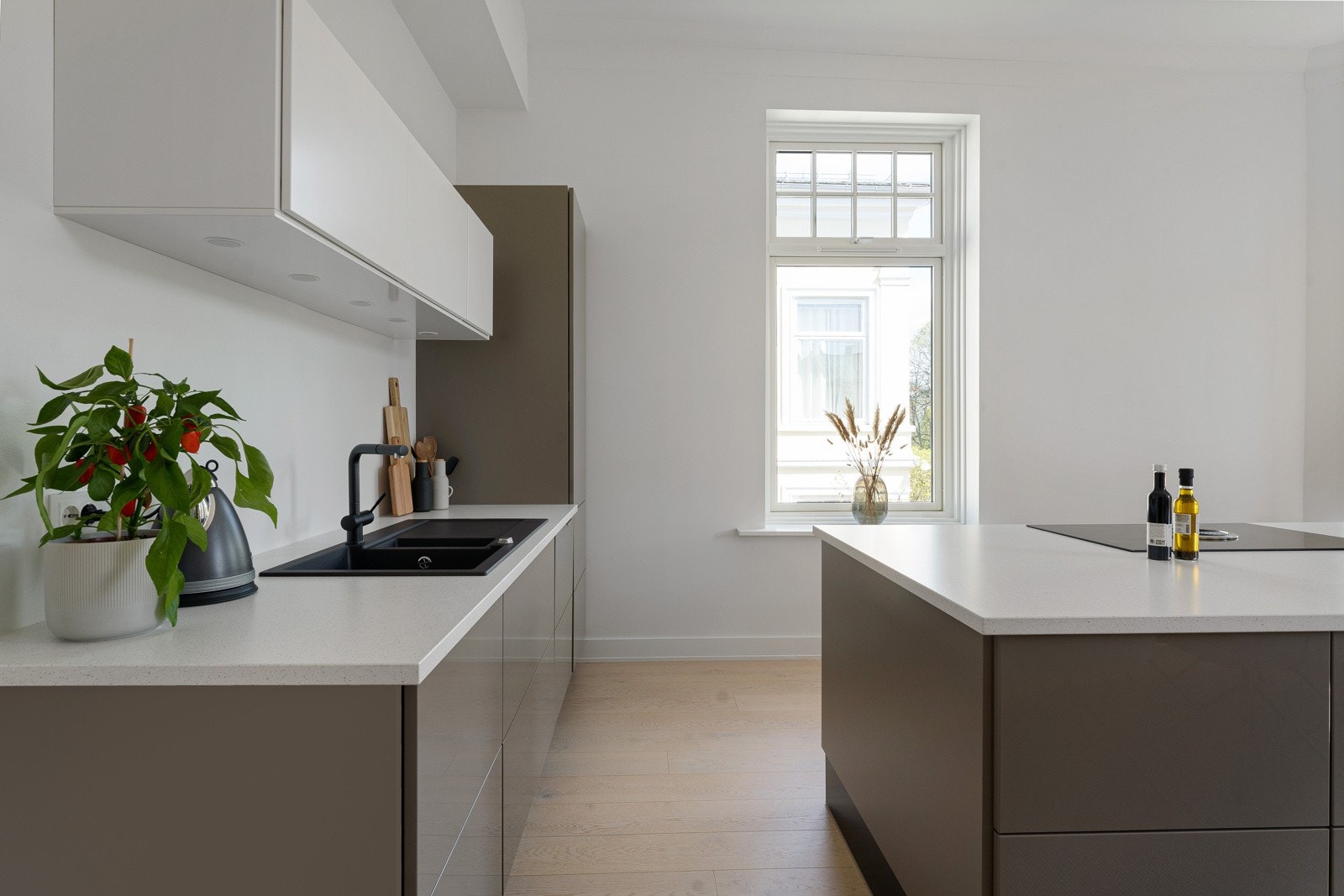 Kjøkkeninnredningen var ny i 2016/17 og har et stilrent, moderne design med håndtaksfrie høyglansfronter, stor kjøkkenøy og integrerte hvitevarer. Skap og skuffer har grå fronter og benkeplatene er i lys stein. Galleribilde