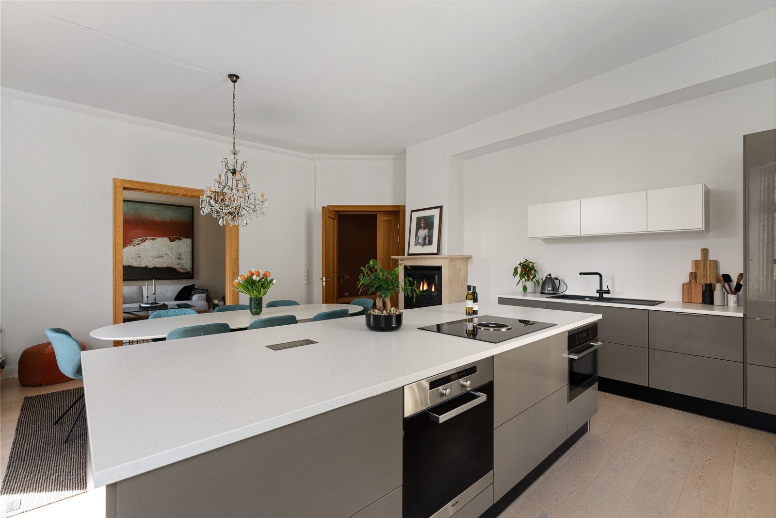 En sort, dobbel oppvaskkum med avrenningsfelt er nedfelt i benk langs veggen, og over er det smale overskap med hvite fronter og benkebelysning. I kjøkkenøya er det nedfelt en Bora induksjonstopp med integrert benkeventilator. Galleribilde