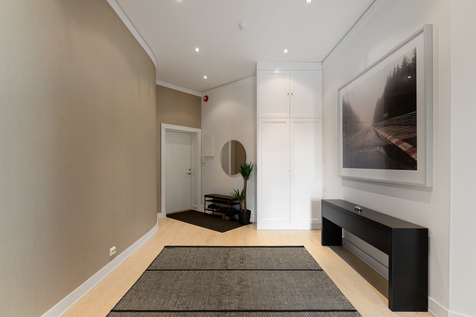 Yttertøy kan ryddes unna i et spesialtilpasset garderobeskap med hvite, profilerte fronter, eller henges bort i gangen innenfor. Galleribilde