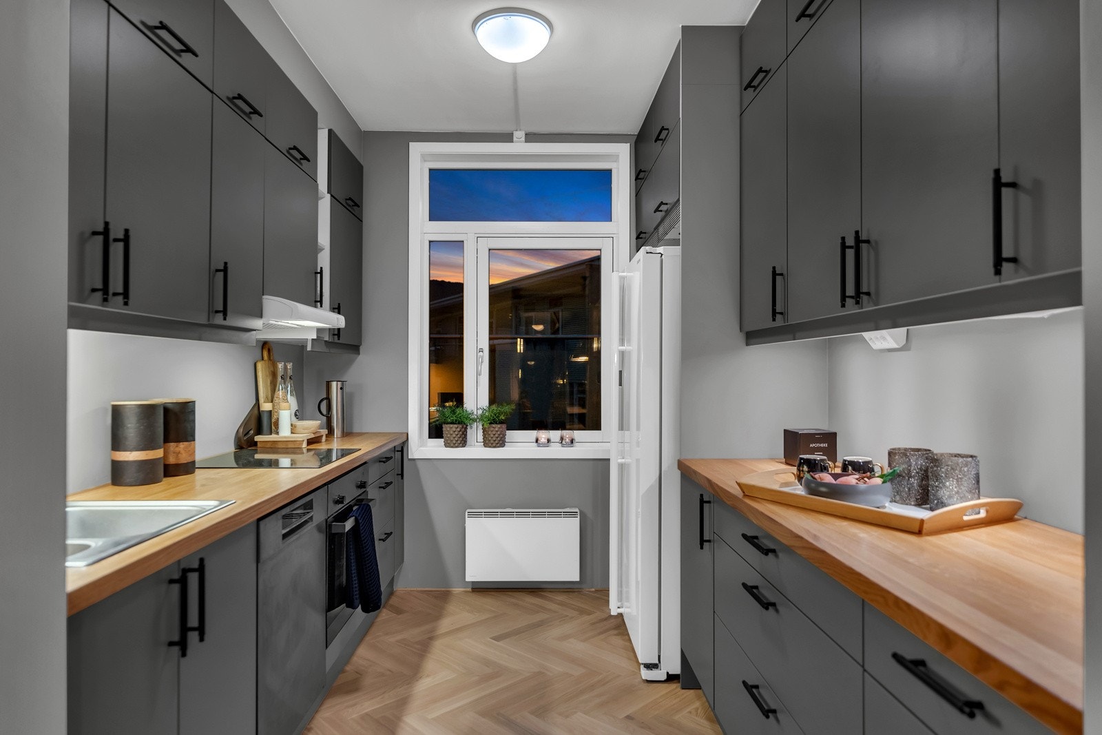 Kjøkkenet er stilrent og innholdsrikt, nylig utvidet med flere overskap fra Norema og oppgradert med ny benkeplate i heltre. Frontene er grå, glatte og har sorte håndtak. Innredningen er plassert på to sider og overskapene er takhøye. Galleribilde