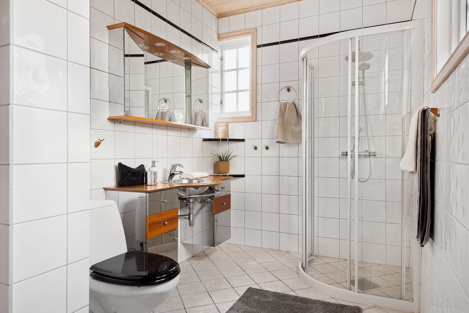 Badet i 1.etasje har fliser på vegger og gulv og er utstyrt med baderomsinnredning, dusjhjørne, toalett og opplegg for vaskemaskin. Galleribilde