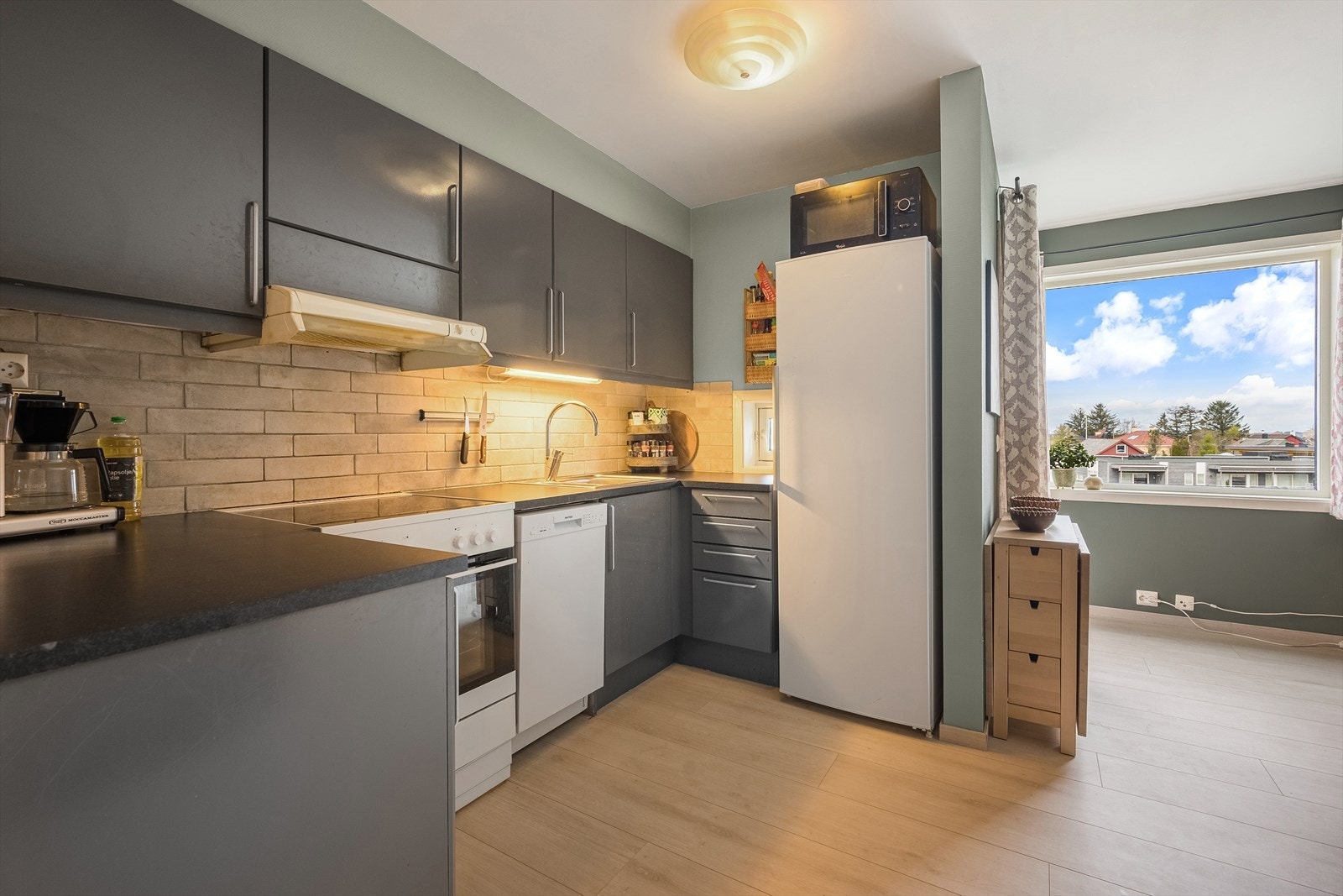 Det er store vindu i stuen som gir ett fint lys inn til kjøkkenet Galleribilde