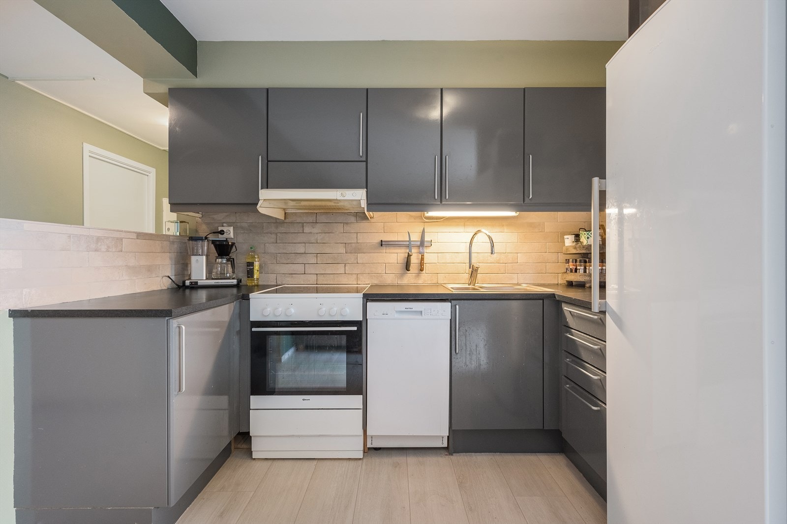 Kjøkkeninnredning har mørke slette fronter, og mørk laminert bankeplate. Galleribilde