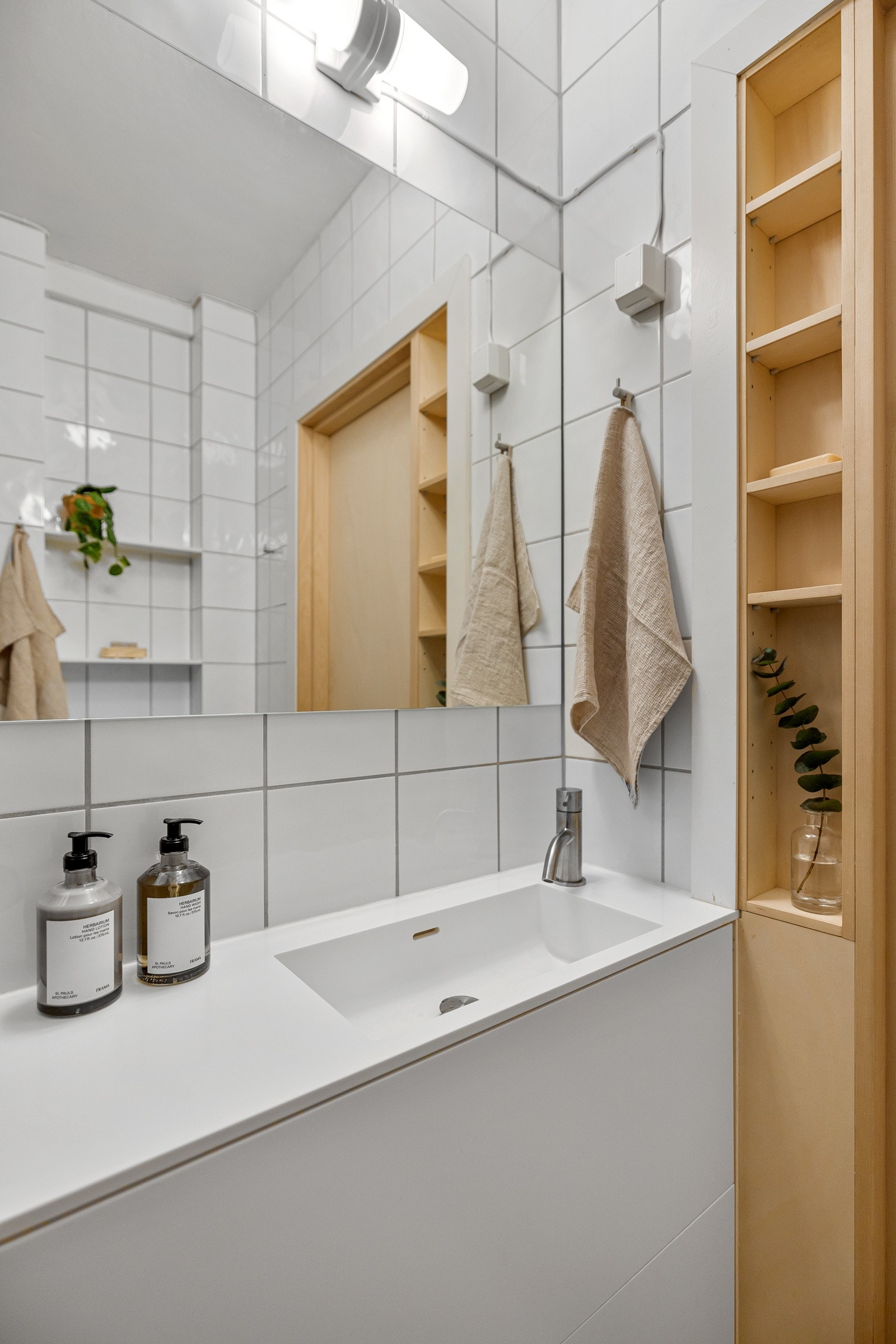 Servantskap med vask av Corian og plassbygde hyller i Corian utført av møbelsnekker i 2022. Nytt spesialbestilt, speil på mål, lampe og stikkontakter fra 2022. Galleribilde