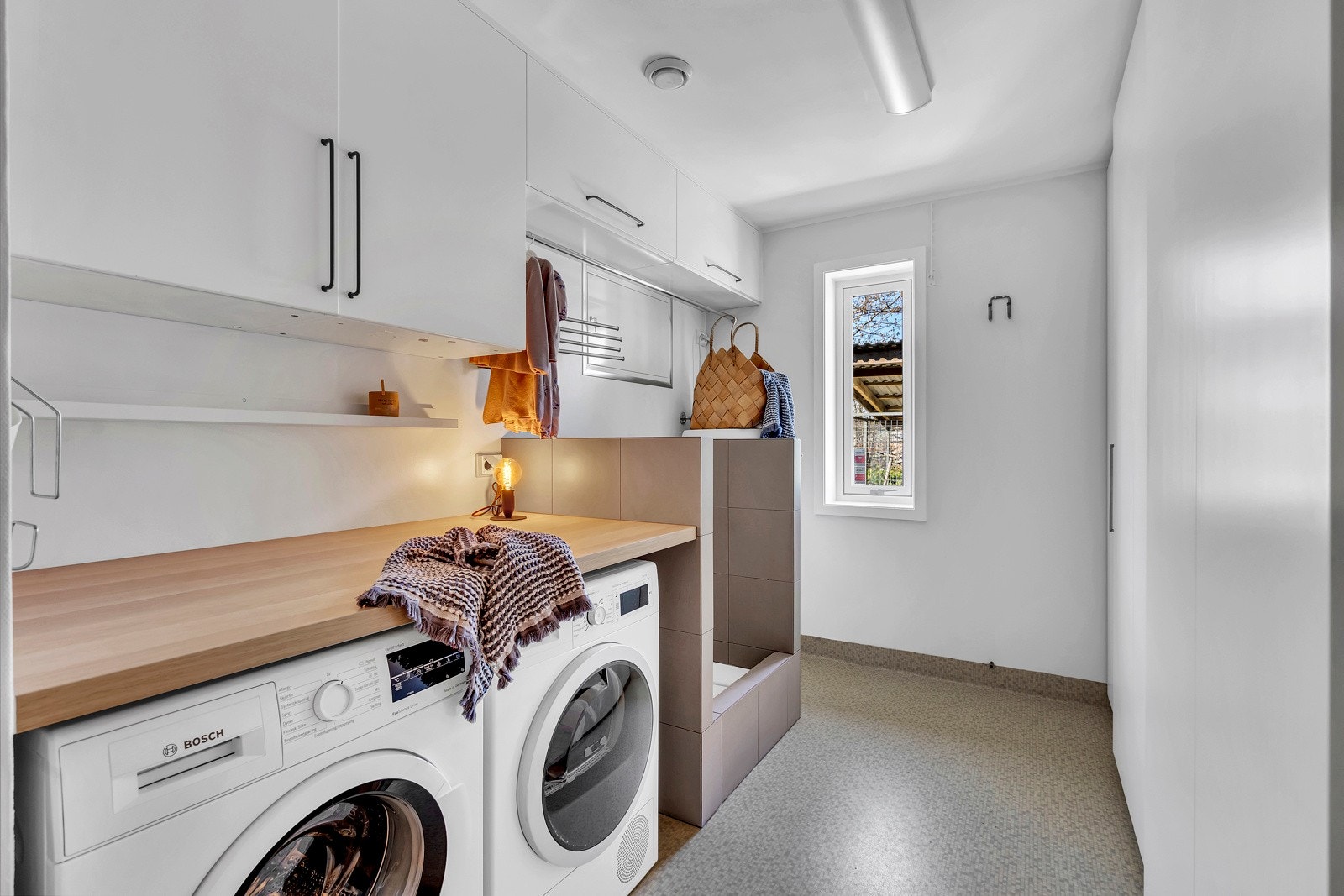 Stort vaskerom med opplegg for vaskemaskin og tørketrommel. Praktisk innredning med arbeidsbenk, skaper og hundedusj. Direkte utgang til garasjen. Galleribilde